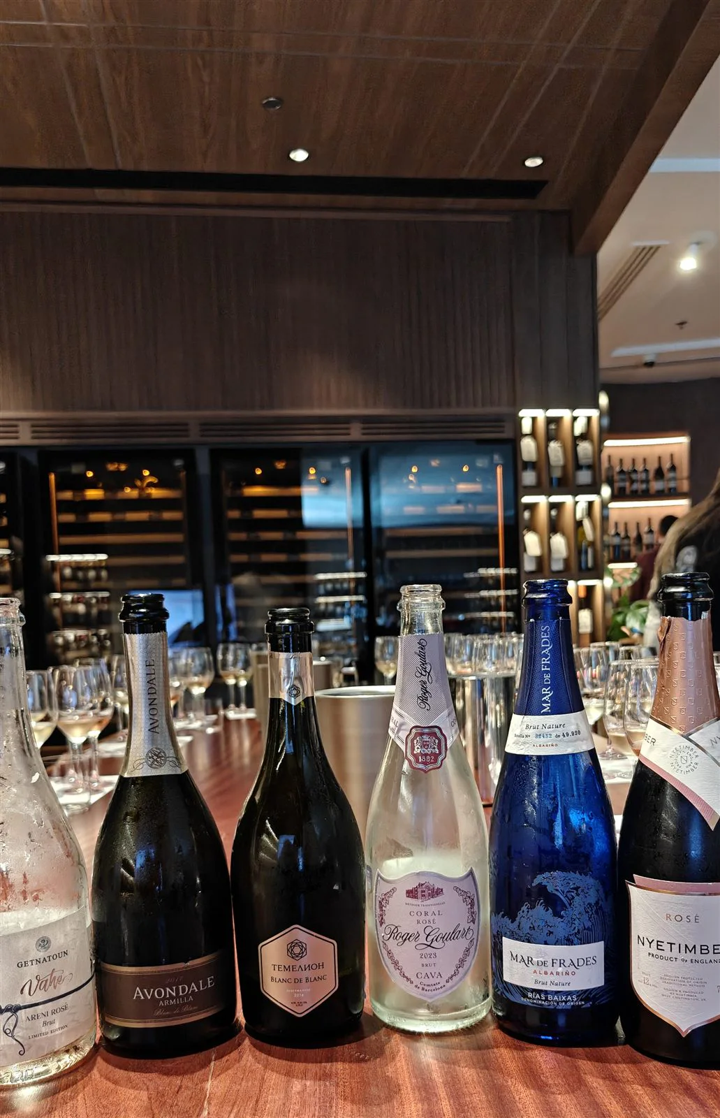 Six sparkling wine bottles lined up at VNTG Wine & Cheese Bar Dubai.